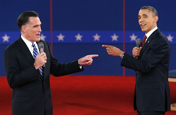 United States Republican presidential nominee Mitt Romney and US President Barack Obama gesture towards each other during the second US presidential debate in Hempstead