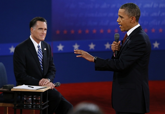 US President Barack Obama answers a questiion as  Romney listens during the second presidential debate in Hempstead, New York