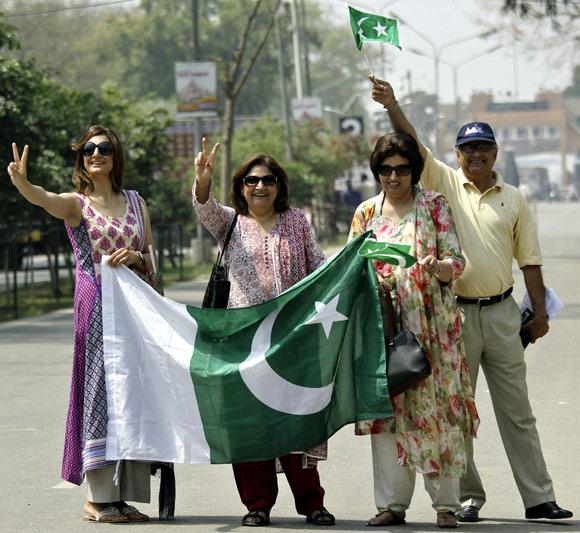 Pakistani visitors wave their national flags as they arrive in India through the check post at Wagah border.