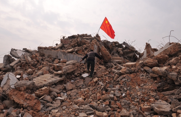 A local resident climbs towards a Chinese national flag planted at the top of his former house in Xi'an, Shaanxi province