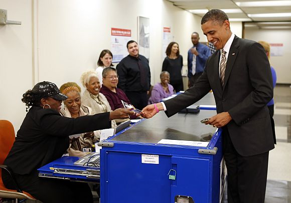 US President Barack Obama shows his drivers licence before casting his vote ballot early at the Martin Luther King Community Centre in Chicago