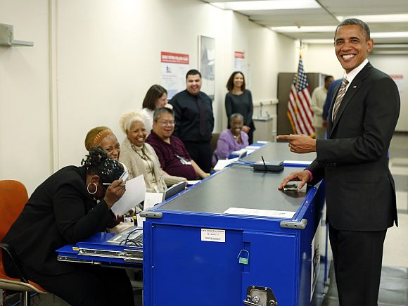 A polling worker laughs after US President Barack Obama mimicked the way she checked the photo on his driver's licence