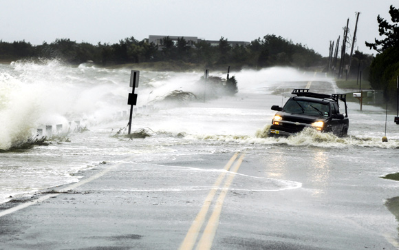 A truck drives through water pushed over a road by Hurricane Sandy in Southampton, New York
