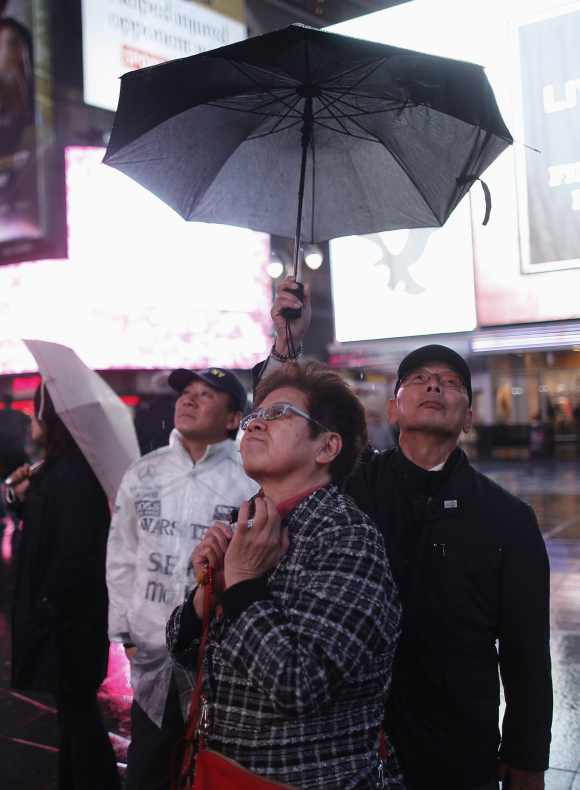 People keep under an umbrella in the mostly deserted Times Square ahead of Hurricane Sandy in New York