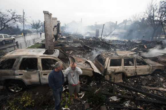 Residents look over the remains of burned homes in the Rockaways section of New York