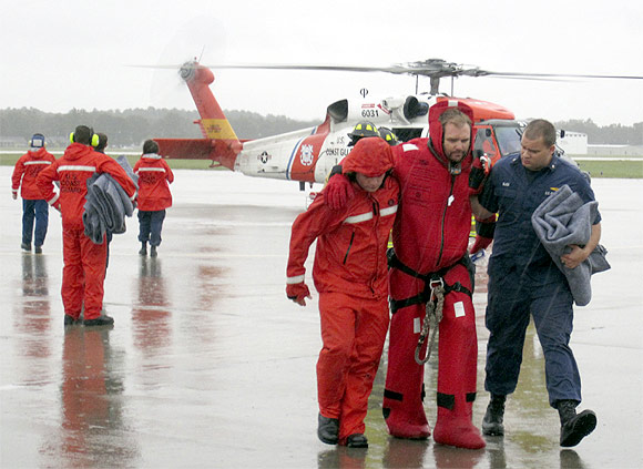 Members of the Coast Guard assist one of the sailors to the runway at the Air Station Elizabeth City, North Carolina. The US Coast Guard rescued 14 of the 16 crew members who abandoned the HMS Bounty off North Carolina in rough seas caused by Hurricane Sandy