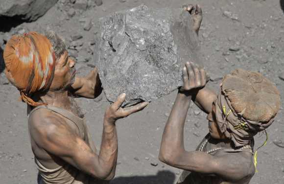 Labourers carry coal to load onto a truck at a coal yard on the outskirts of the northern Indian city of Allahabad