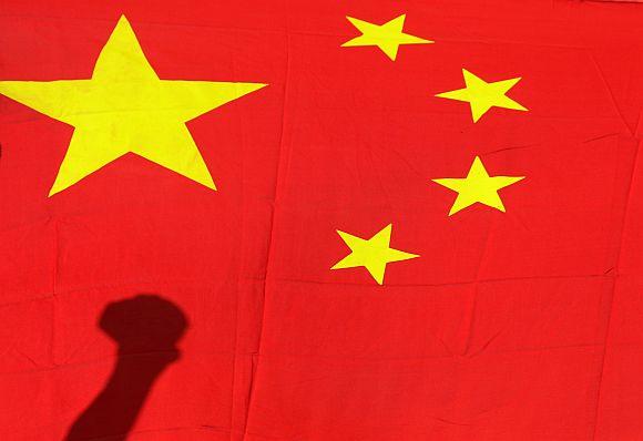 Shadow of clenched fist of protester is seen on Chinese national flag during anti-Japan protest in Beijing