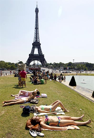 People sunbathe on the grass near the Eiffel Tower, Paris