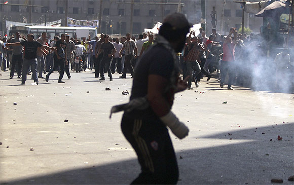 Anti-Mursi protesters run as supporters of Egypt's President Mohamed Mursi throw stones at each other during clashes in Tahrir Square in Cairo
