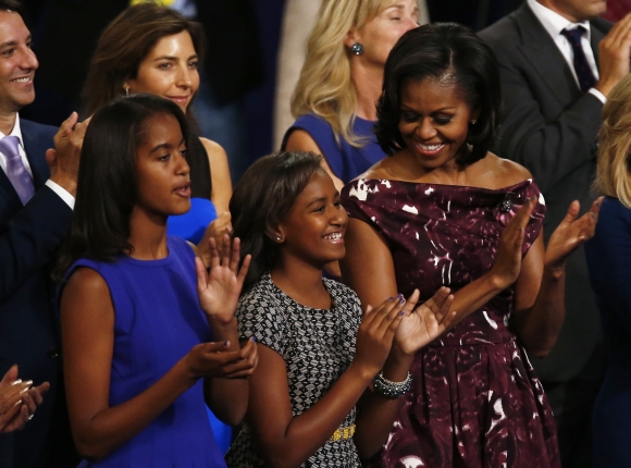 First Lady Michelle Obama applauds with daughters Malia and Sasha