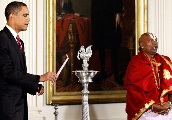 US President Barack Obama lights a traditional oil lamp as Sri Narayanachar Digalakote, Hindu priest from the Sri Siva Vishnu Temple in Maryland, chants in observance of Diwali in the East Room at the White House October 14, 2009 in Washington, DC