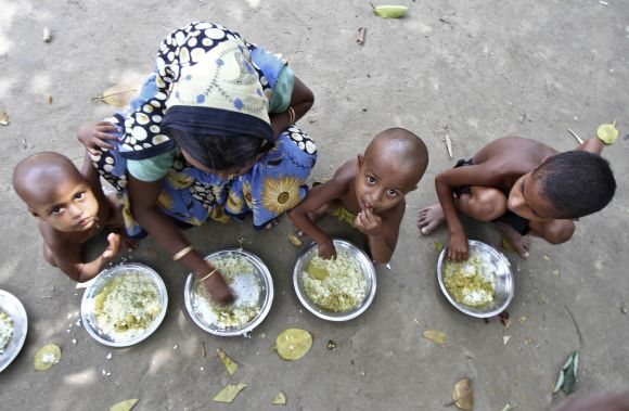 Villagers affected by ethnic riots eat their community lunch inside a relief camp near Bilasipara town in Assam