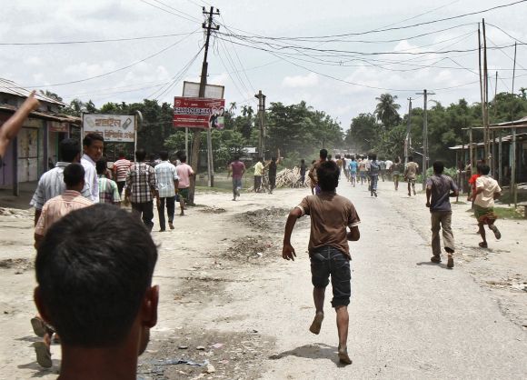Villagers affected by ethnic riots run after the Assam legislative assembly team during their visit at a relief camp in Assam