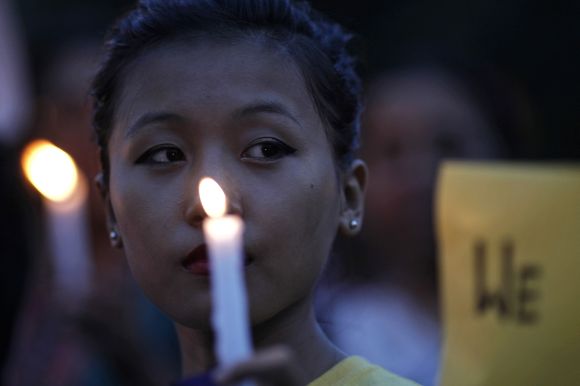 Woman holds candle during vigil to show solidarity with the people of Assam at a rally in front of the India Gate in New Delhi