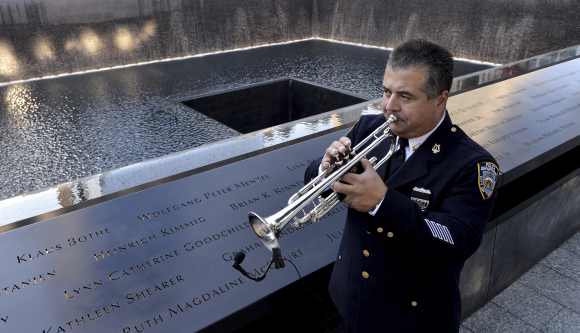 New York City police bugler Gabe Perdomo warms up while standing next to the South Pool