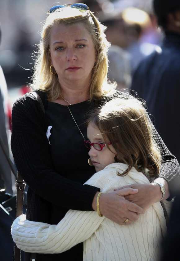 Nina Fisher, sister of 9/11 victim Andrew Fisher, embraces her niece Mia Tinson, 9, during a ceremony at the WTC