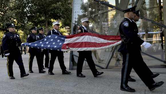 Port Authority Police Officers carry the US flag that flew at the World Trade Center towers during a 9/11 ceremony