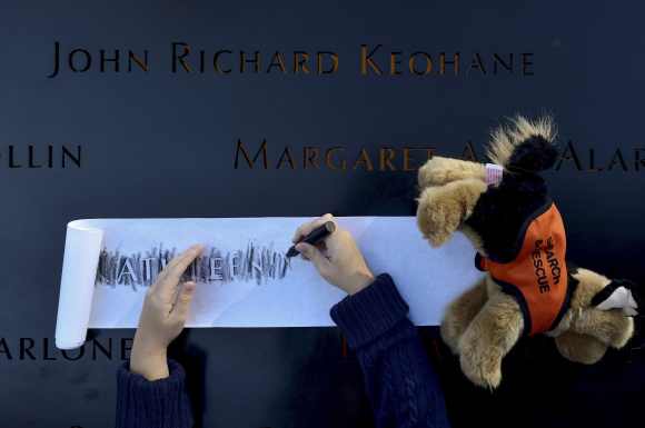 Ava Kathleen Schmoelzer, 7, makes a rubbing of her late aunt's name, Kathleen Moran at the WTC