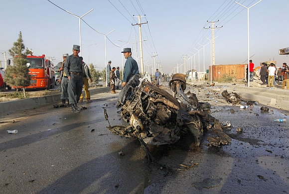 Afghan police stand near the wreckage of a vehicle which was used by a suicide bomber near Kabul