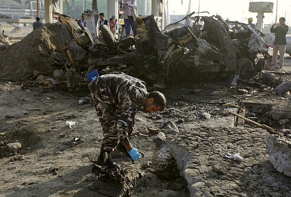 An Afghan security officer investigates the site of the suicide attack