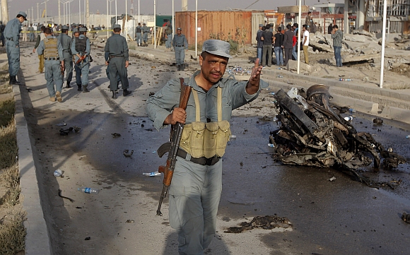 An Afghan police officer keeps people away from the site of a suicide attack in Kabul
