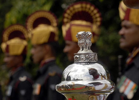 An Indian soldier is reflected on an official emblem of the Government of India