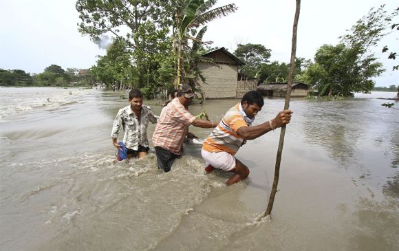 Villagers cross a flooded road at Lachi Bishnupur village in Assam.