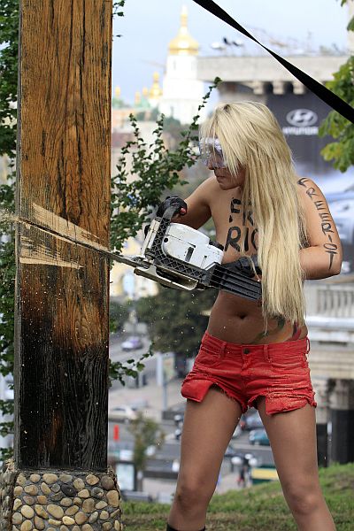 An activist from women's rights group Femen uses a chainsaw to cut down a Christian cross, erected in memory of victims of political repressions under the Soviet dictator Josef Stalin regime, near the Oktyabrsky Palace in central Kiev