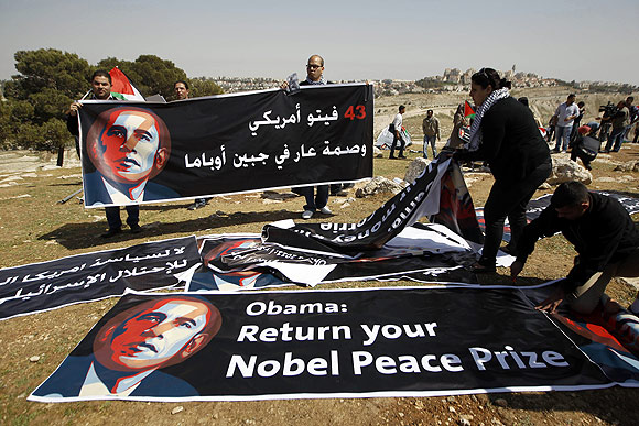Palestinian activists organise banners depicting US President Barack Obama at a protest camp