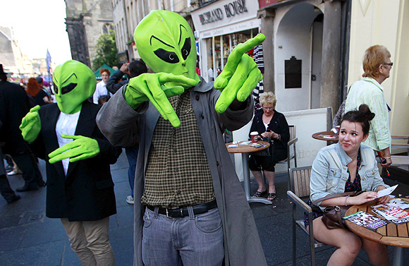 Actors dressed wearing alien masks walk among the public in the Royal Mile during the Edinburgh Festival Fringe in Edinburgh