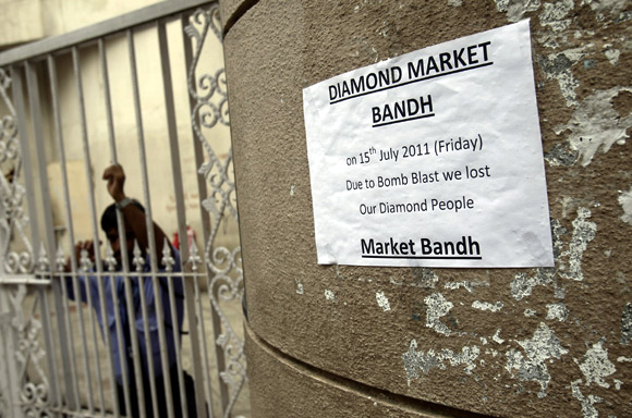 A private security guard stands next to a sign that says the diamond market in Zaveri Bazaar is temporarily shut