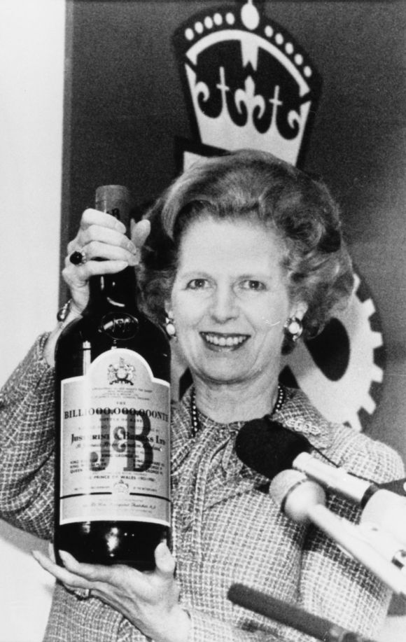 British Prime Minister Margaret Thatcher holds a three litre bottle of scotch whisky which was presented to her after a tour of a whisky distillery