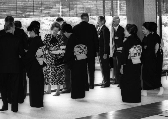 In her stocking feet at the Japanese style dinig room at Akasaka Palace on May 5, 1986, British Prime Minister Margaret Thatcher presents a picture of contrast to the kimono-clad, sandle-wearing hostess