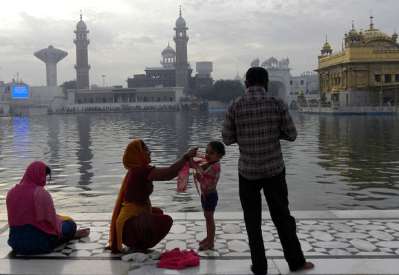 A little tyke has her first dip in the Amrit Sarovar. Her father captures the occasion on his cell phone