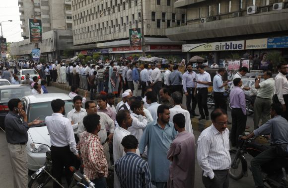 People stand outside of their office buildings following an earthquake tremor in Karachi