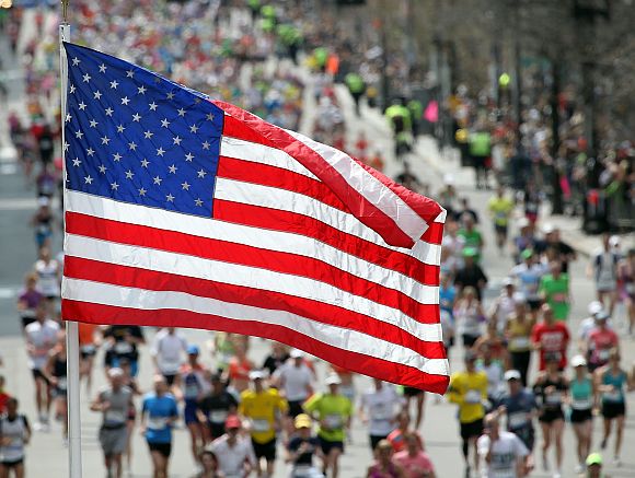 An American flag is seen as runners make their way to the finish line during the 117th running of the Boston Marathon