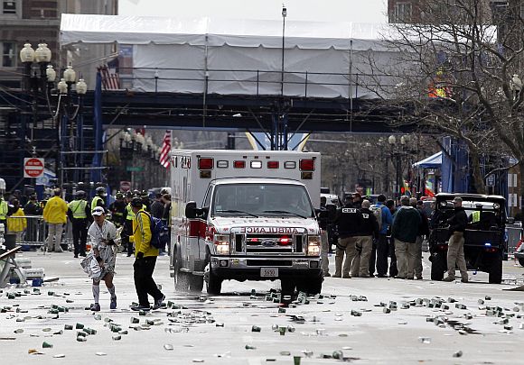 A runner is escorted from the scene after explosions went off at the 117th Boston Marathon in Boston