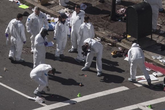 Investigators survey the site of a bomb blast on Boylston Street a day after two explosions hit a marathon in Boston, Massachusetts
