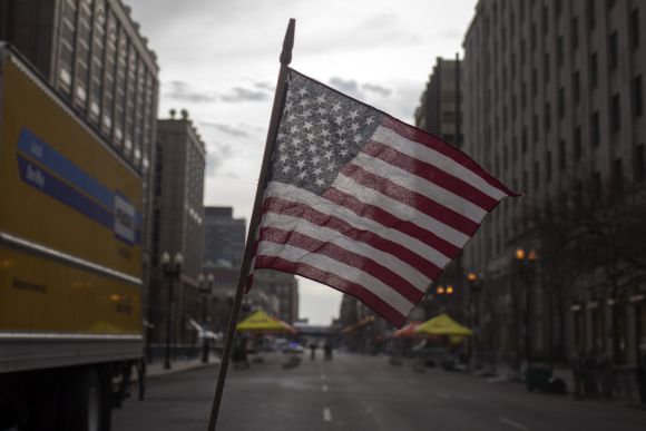 An American flag waves from a make shift memorial on Boylston Street a day after Boston blasts
