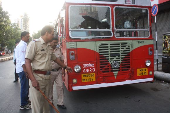 Police inspect a damaged bus as bandh against the ongoing demolition drive paralysed life in Thane on Thursday