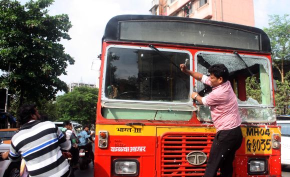 A protestor attacks a government bus as normalcy was crippled during Thursday's Thane bandh