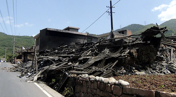 Collapsed houses are seen after an earthquake of 6.6 magnitude, on the side of a road leading from Ya'an city to Luzhou County