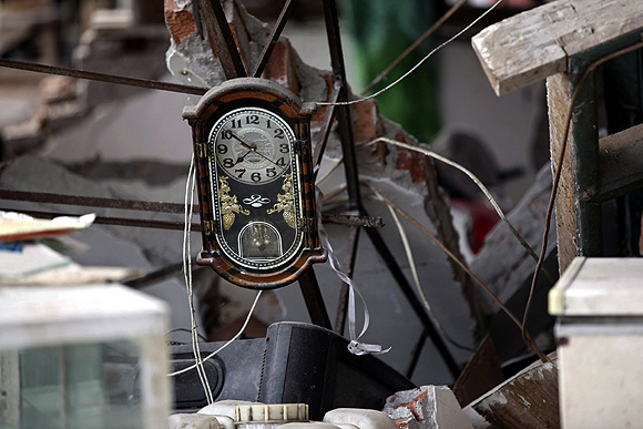 A clock is seen amidst the debris of a collapsed house after a strong 6.6 magnitude earthquake, at Longmen village, Lushan County