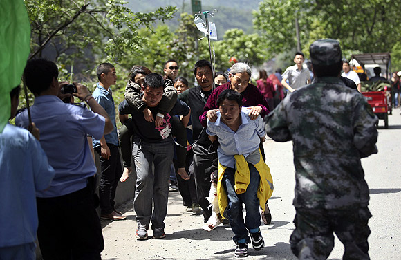 Men carry injured people to an ambulance at Longmen Village, Lushan County
