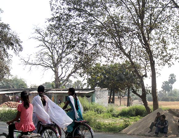 Girls cycle on a road in North Bihar