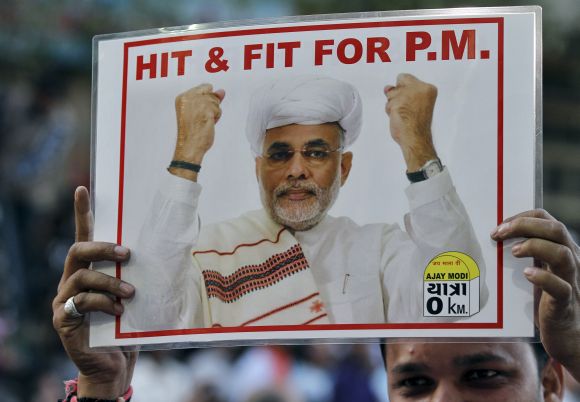 A BJP supporter holds a poster featuring Narendra Modi during a jubilation ceremony outside the party office in Ahmedabad.