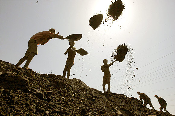 Labourers load coal on trucks at a mine