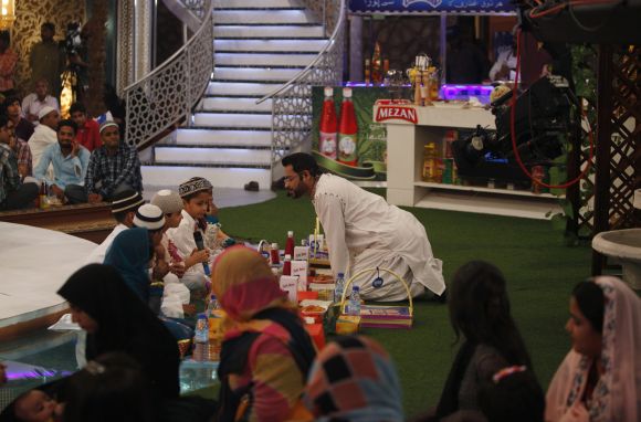Aamir Liaquat Hussain, host of the Geo TV channel programme Amaan Ramazan, talks to children who are fasting for Ramadan for the first time, during a live show in Karachi