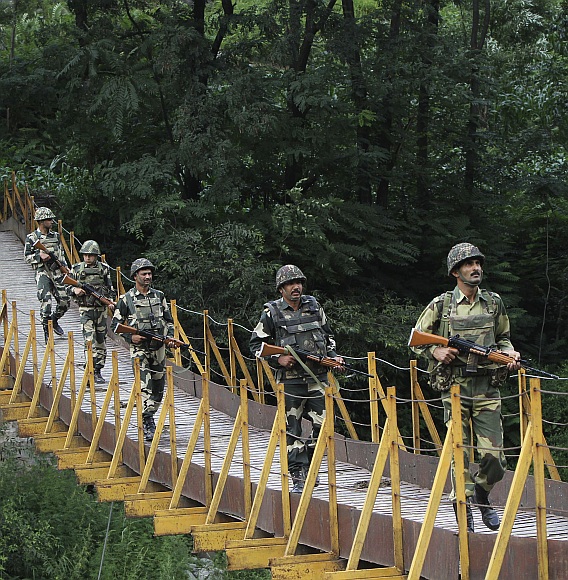 Border Security Force soldiers patrol over a footbridge built over a stream near the Line of Control, a ceasefire line dividing Kashmir between India and Pakistan, at Sabjiyan sector of Poonch district